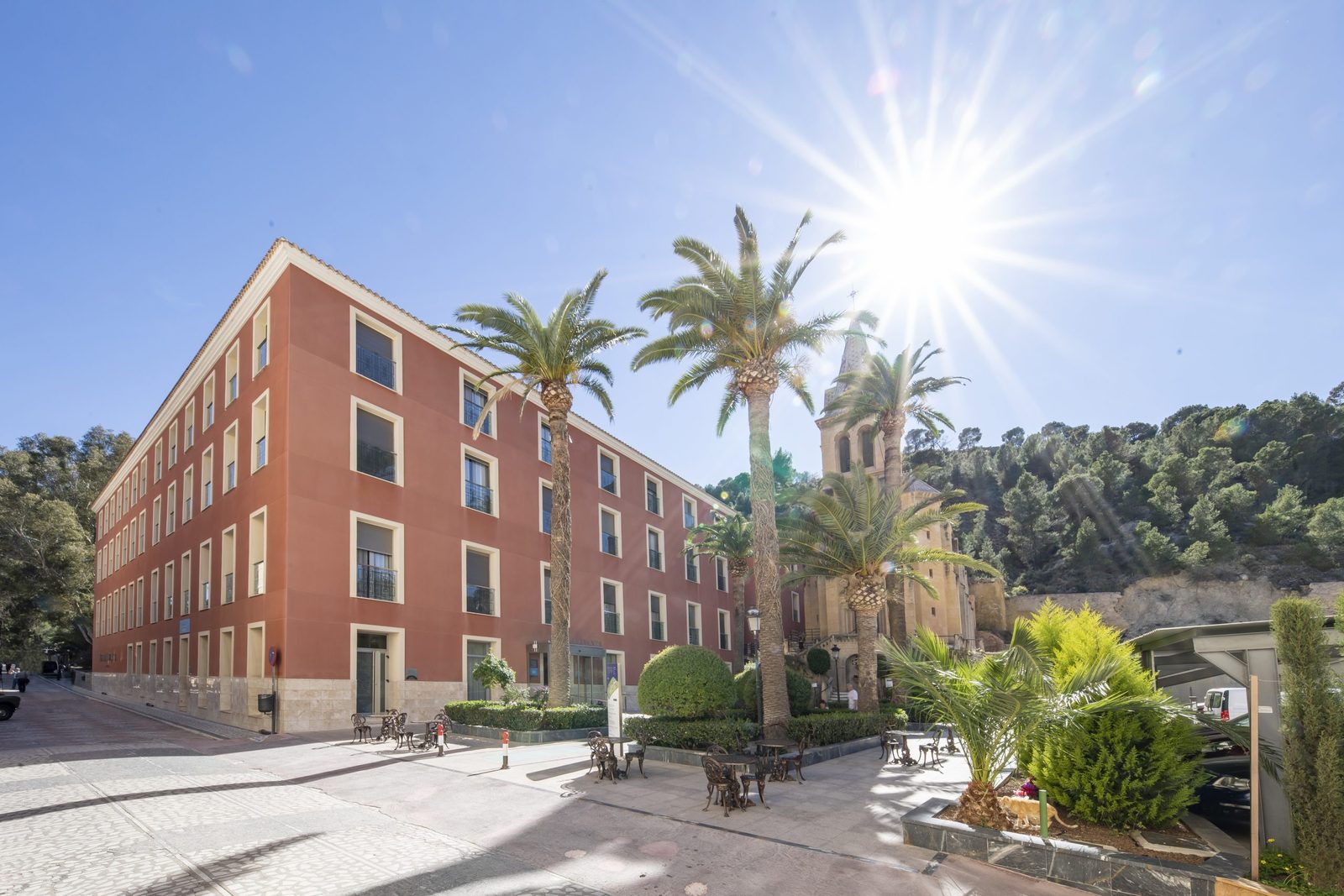 Здание Hotel Levante в парке с пальмами